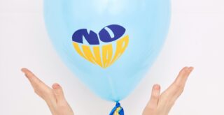 Blue balloon labeled 'No War' held by hands symbolizing peace and Ukraine support.